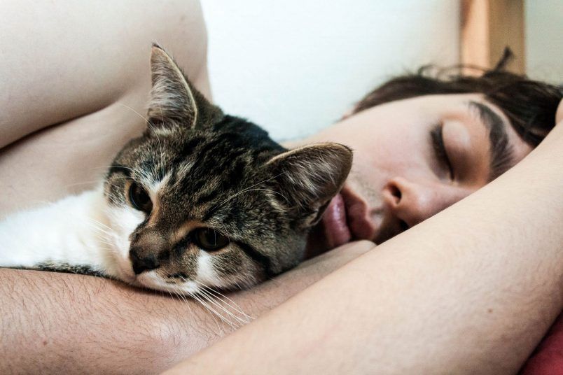 Una mujer duerme con su gato. Llega el cambio de hora: ¿podremos dormir una hora más o una hora menos?