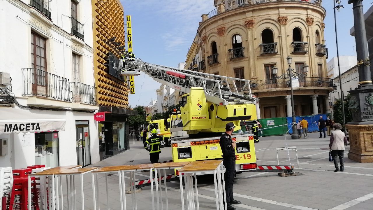Los bomberos, actuando en Ulloa Óptico para evitar la caída del cartel, en calle Larga.