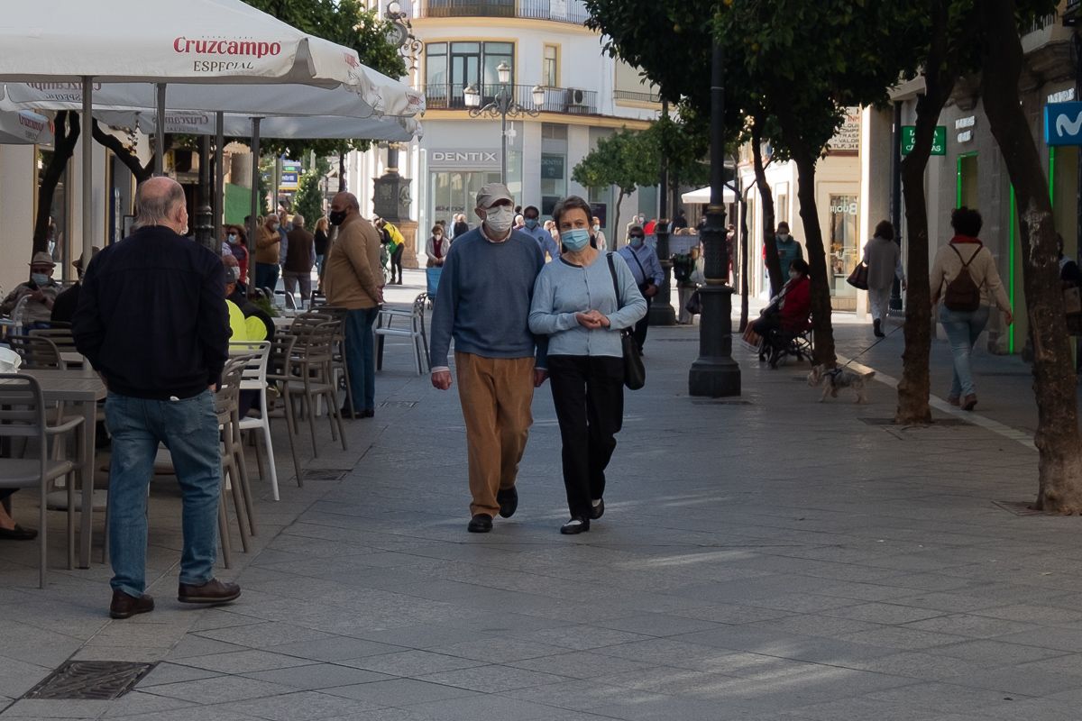 Varias personas pasean por calle Larga en Jerez durante la pandemia, junto a las terrazas de los bares.