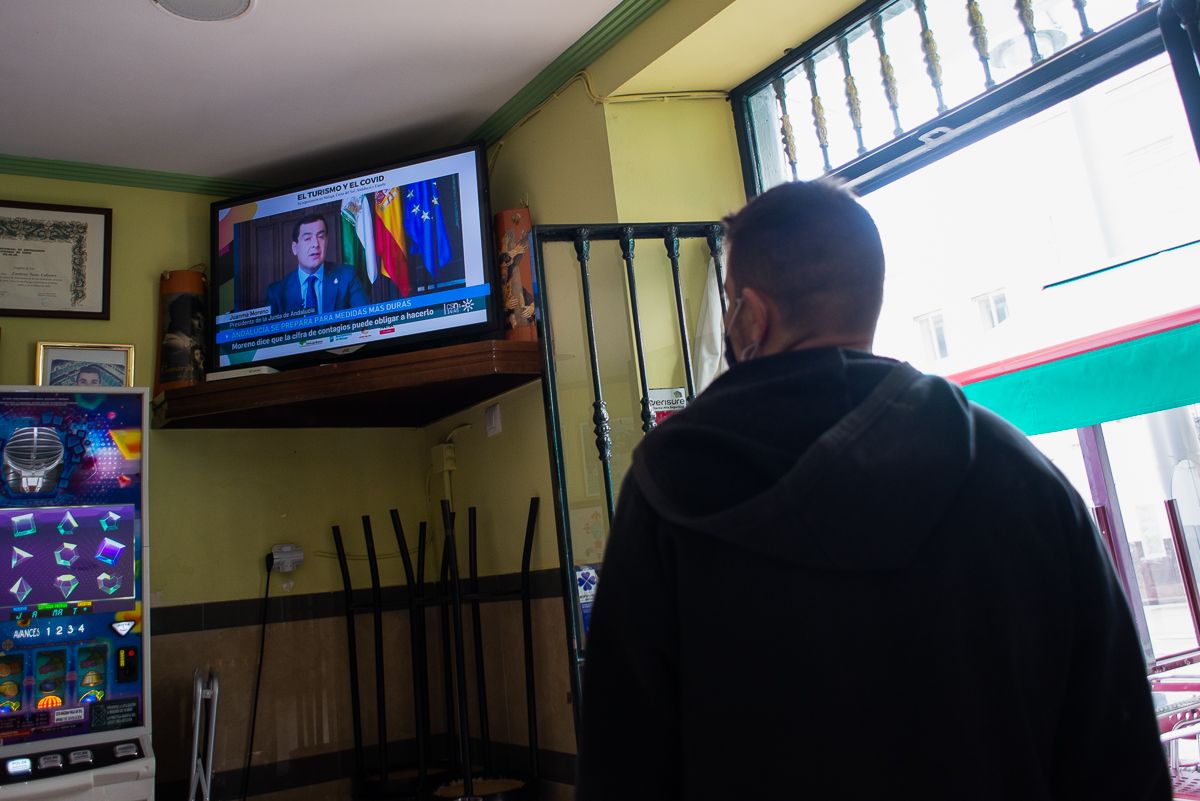 Un vecino de San Fernando observa en un bar una intervención de Moreno Bonilla. 
