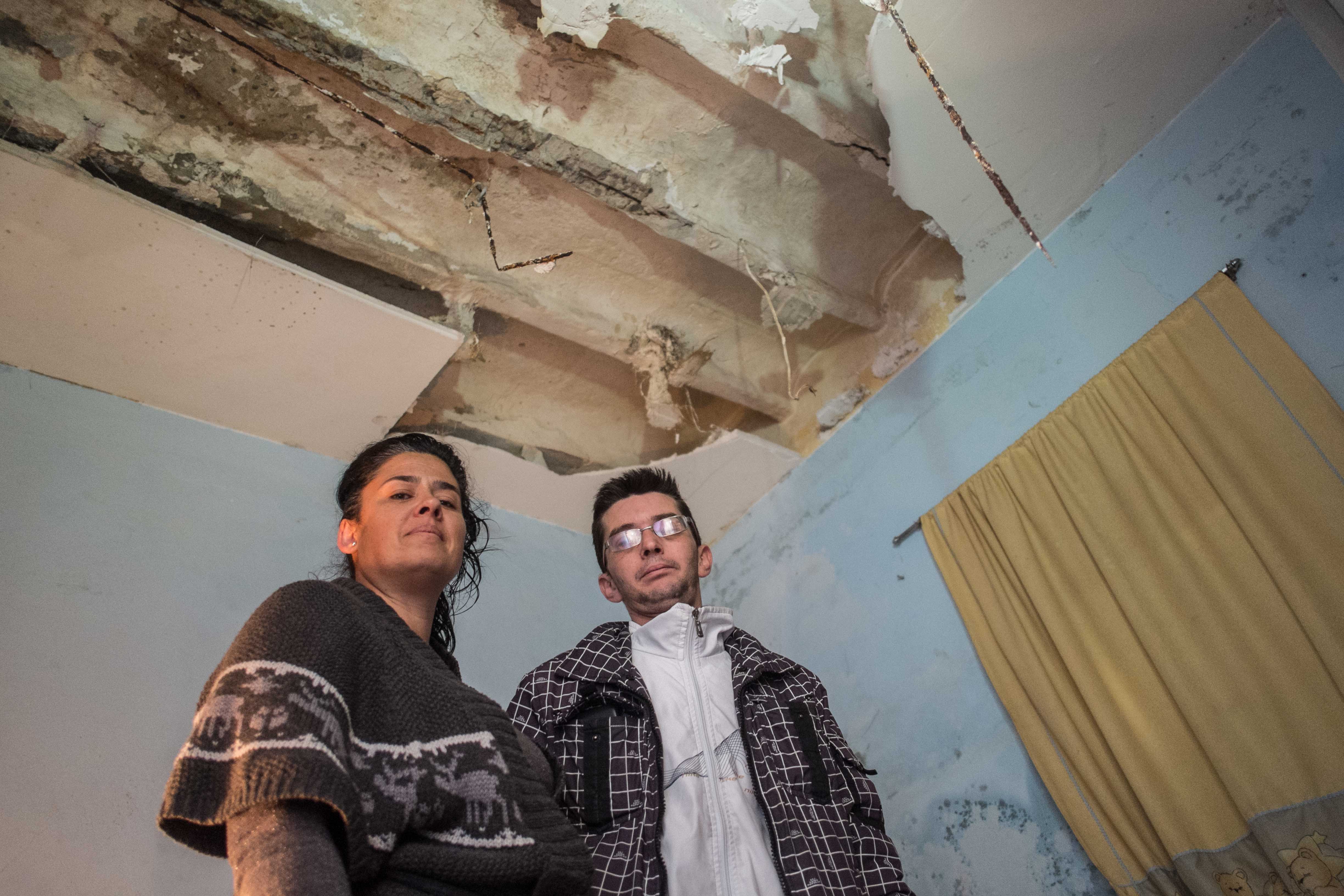 Yolanda y José Antonio posan bajo el techo derrumbado de la habitación de sus dos hijos menores. FOTO: MANU GARCÍA