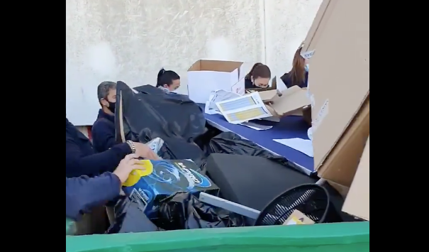 Trabajadores de LTK, buscando sus pertenencias en un contenedor de basura.