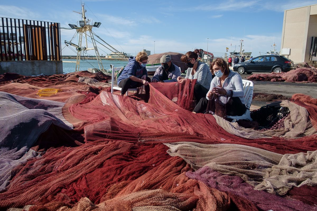Las rederas Manoli, Rosa y María José, atendiendo a las explicaciones de Rafael en el puerto de Barbate.