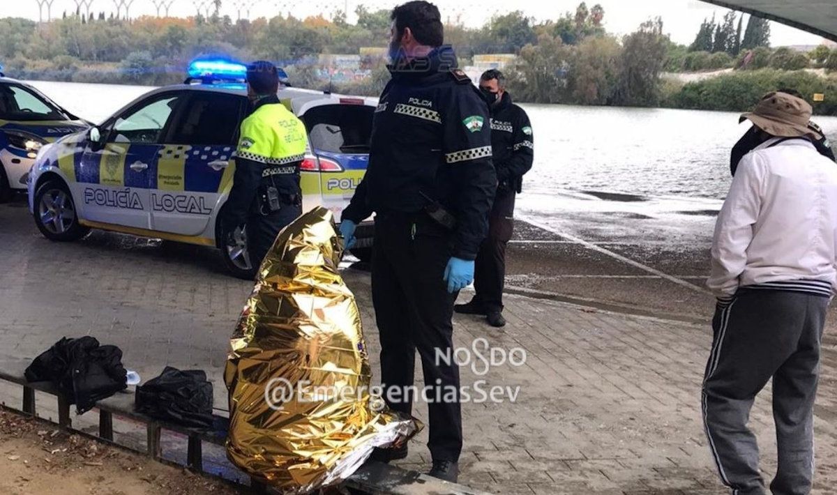 Agentes de la Policía local con la mujer rescatada en la dársena del río en Sevilla.