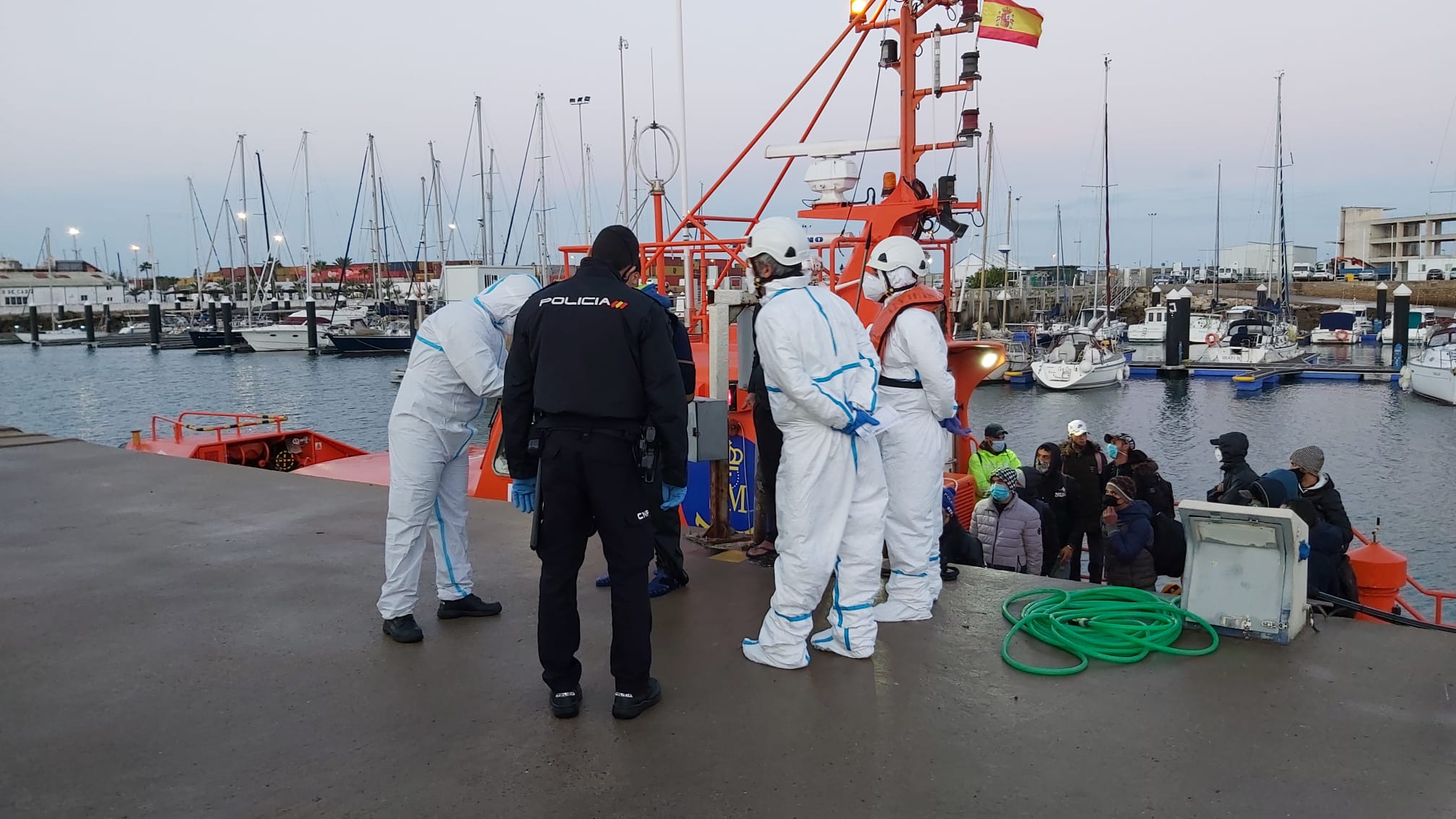 Inmigrantes llegados en patera a Costa Ballena, atendidos por agentes y personal de emergencias.