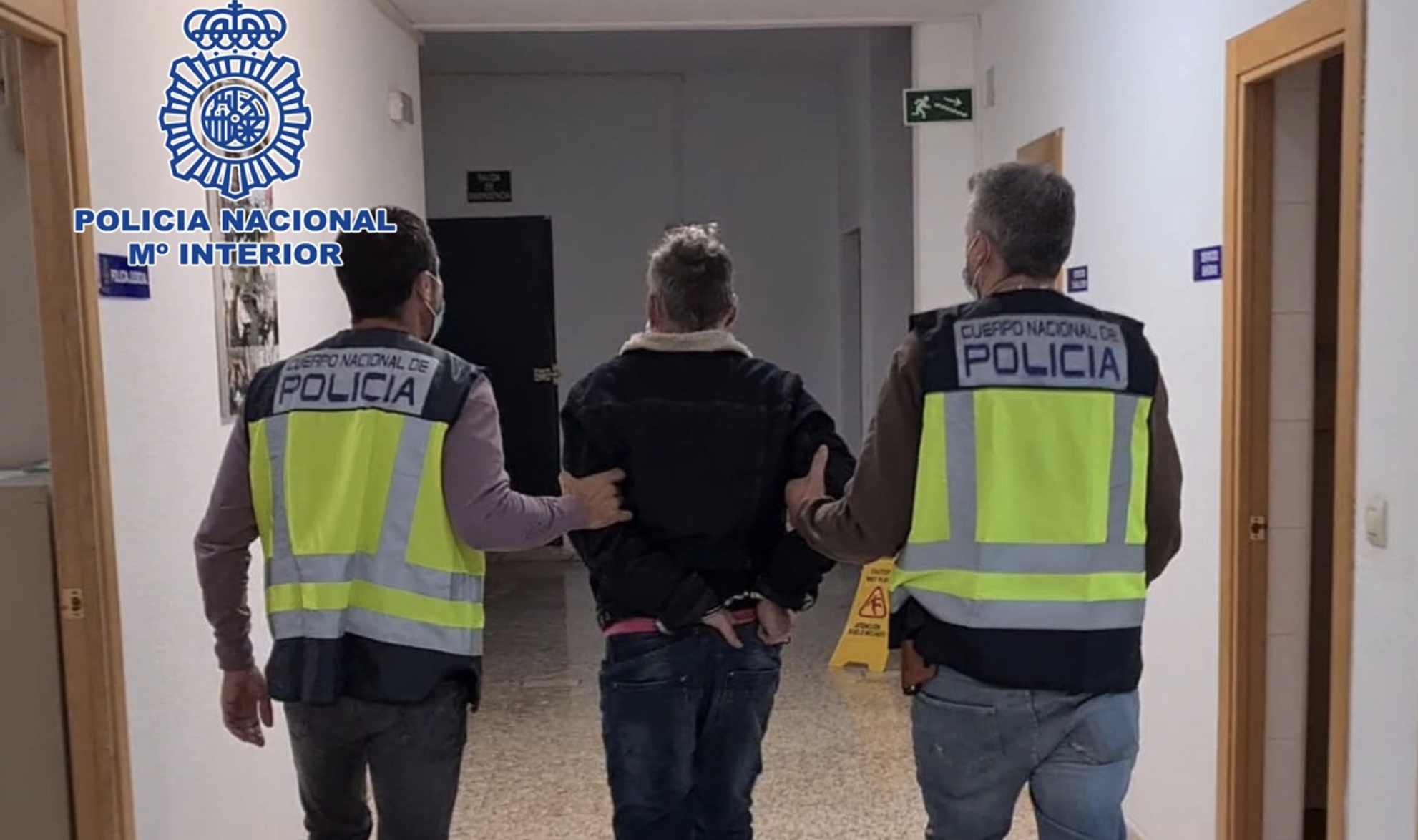 Uno de los detenidos es conducido por agentes de la Policía.
