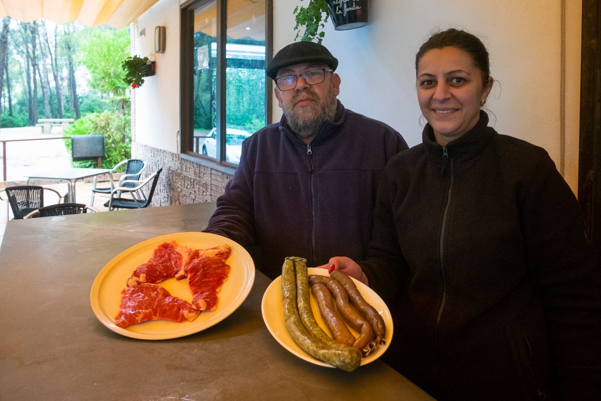 Brígido Mera, con sus carnes y sus chistorras, en el bar de Las Aguilillas, junto a su pareja, Juana Blasa, que también trabaja en el establecimiento.