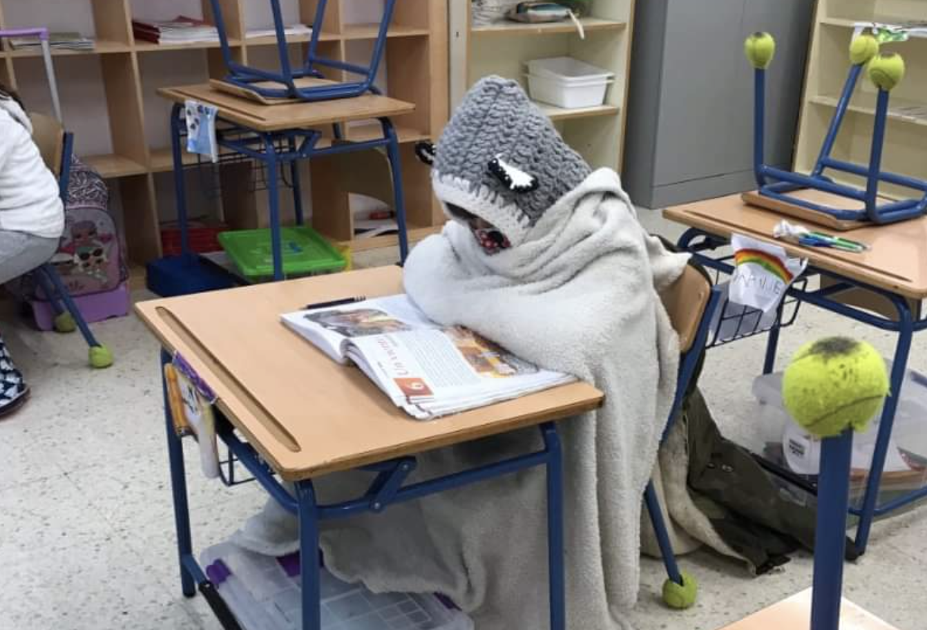 Estudiante hasta arriba de ropa de abrigo para combatir el frío en un aula en pandemia.
