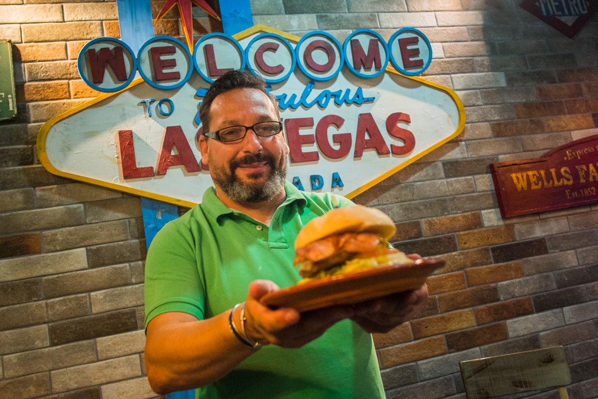 Ale Girón con la hamburguesa Doble Gouda, posando en el interior de su restaurante Salsa Chips. FOTO: MANU GARCÍA. 