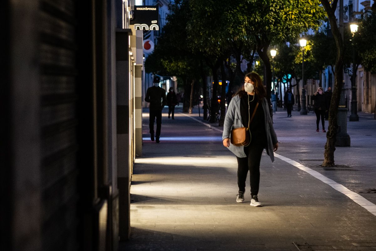 Una persona pasea frente a unos escaparates iluminados en Jerez, durante la pandemia.