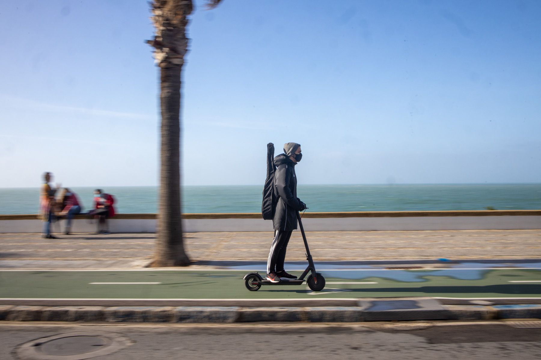 Una persona pasa con el patín eléctrico por el carril bici de Cádiz.