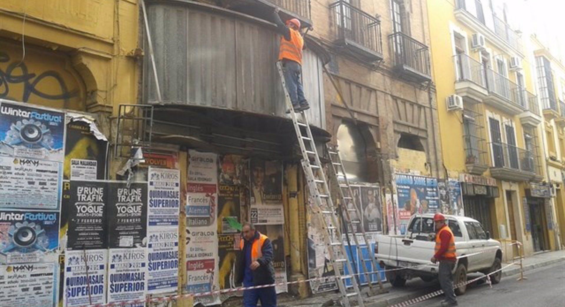 Un momento de la retirada del cartel del antiguo cine X de la calle Trajano de Sevilla.