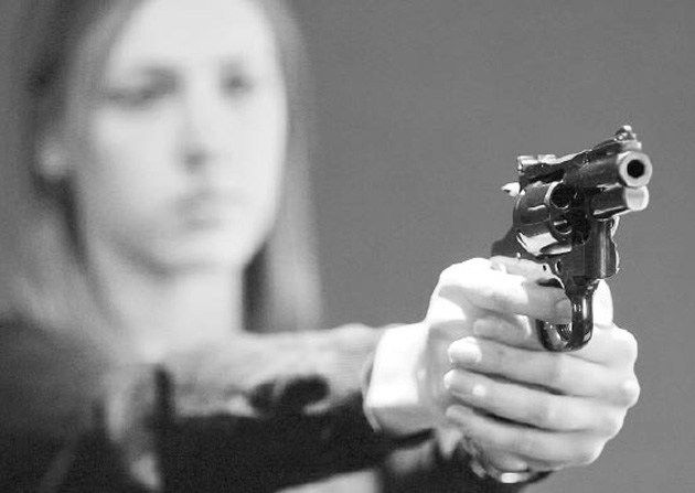 Una mujer apuntando con una pistola. 