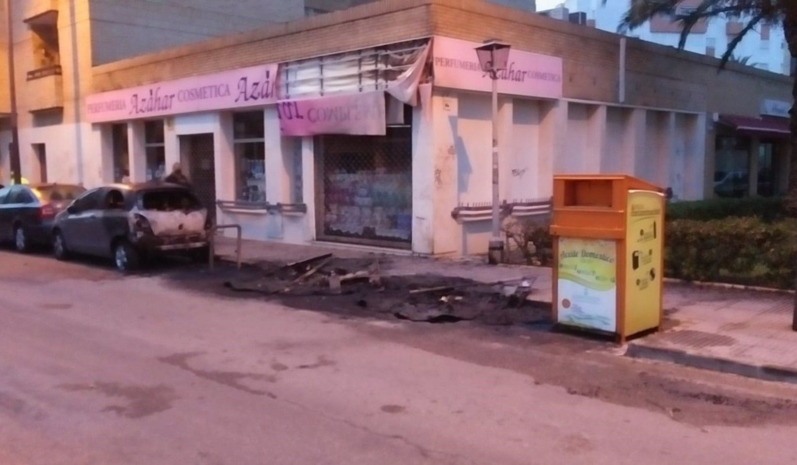 Contenedores calcinados, con un negocio y un vehículo con daños.