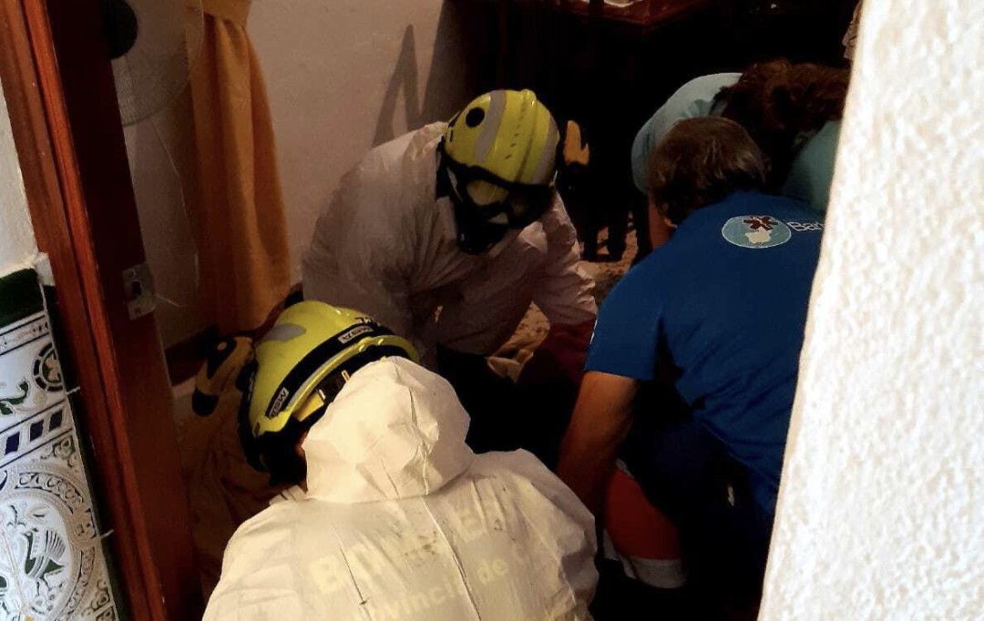 Bomberos atienden a la anciana una vez han podido acceder a la vivienda. CONSORCIO BOMBEROS
