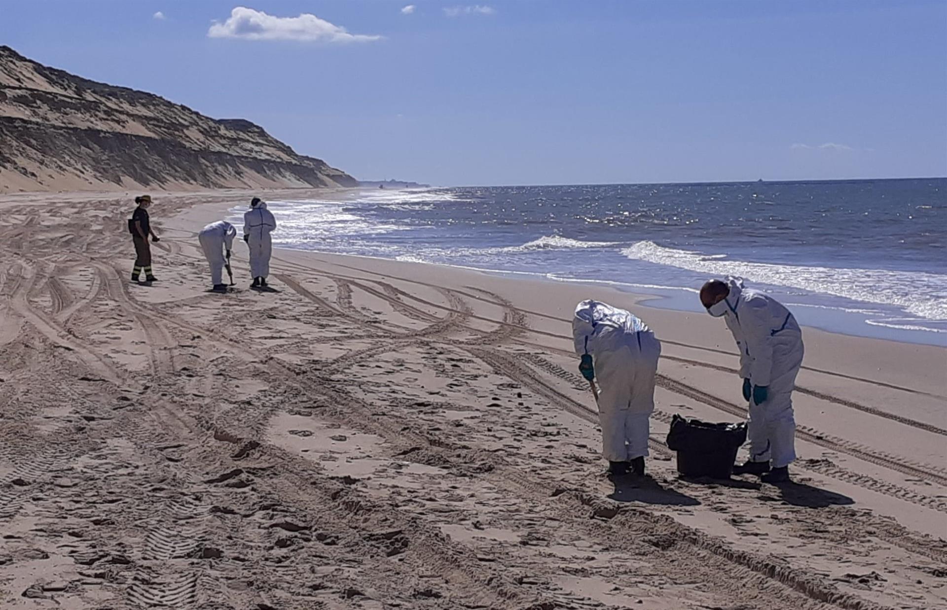 Miembros de uno de los equipos de recogida de los restos de la mancha de hidrocarburos trabajan en la zona de Matalascañas. INFOCA