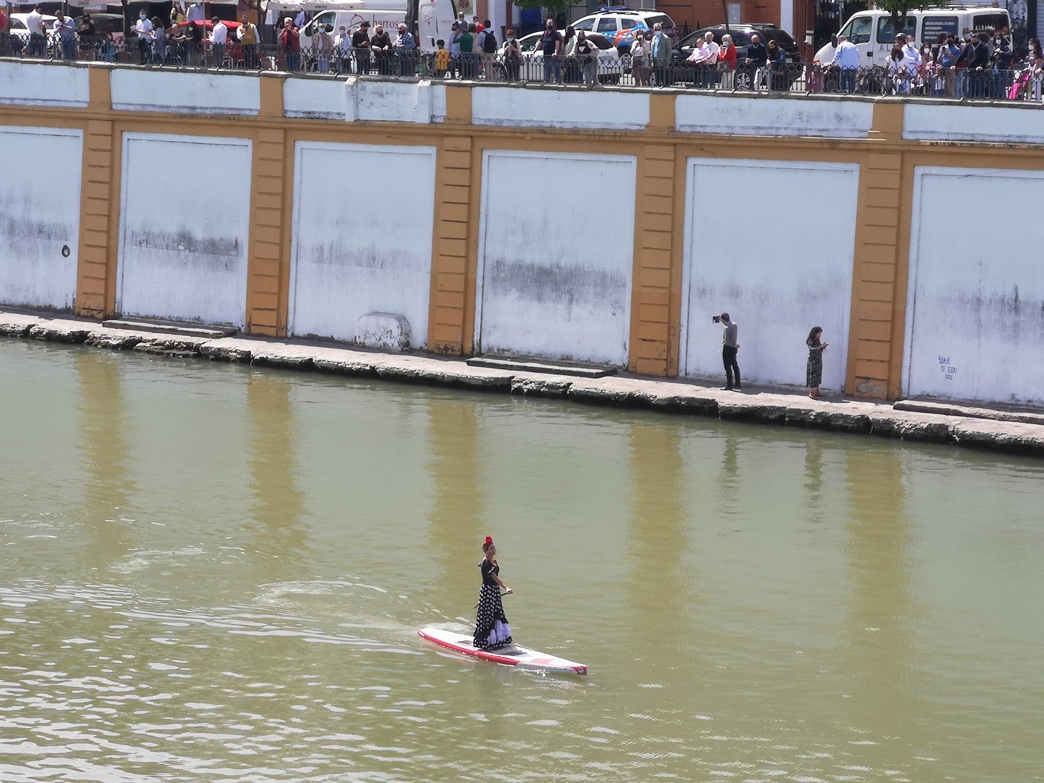 Ibis María Palomo, vestida de flamenca haciendo paddle surf.