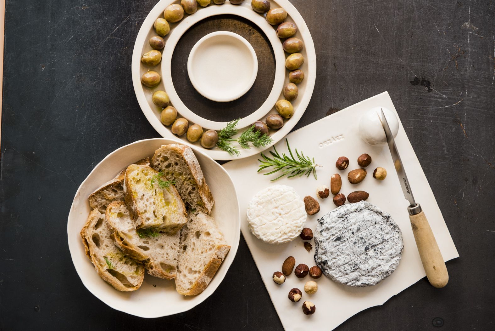 Aceitunas ecológicas, pan de masa madre y quesos de Mare Nostrum sobre los platos realizados por 'Virgen Cerámica'.   MAURI BUHIGAS