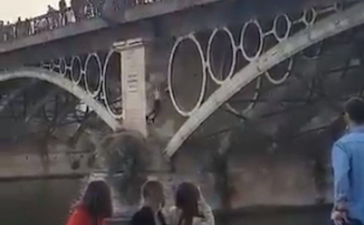 Un individuo salta al río desde el puente de Triana de Sevilla.