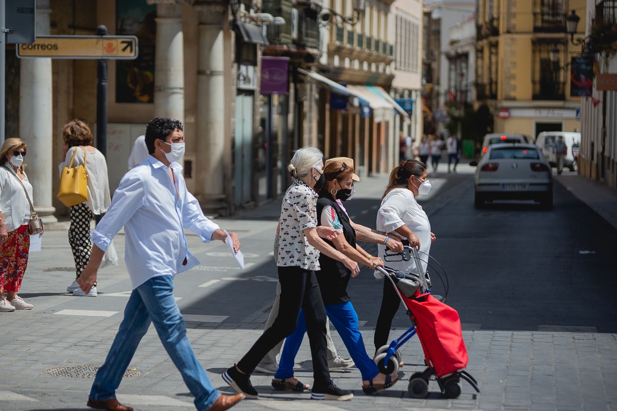 Varias personas, andando con mascarilla por la calle.