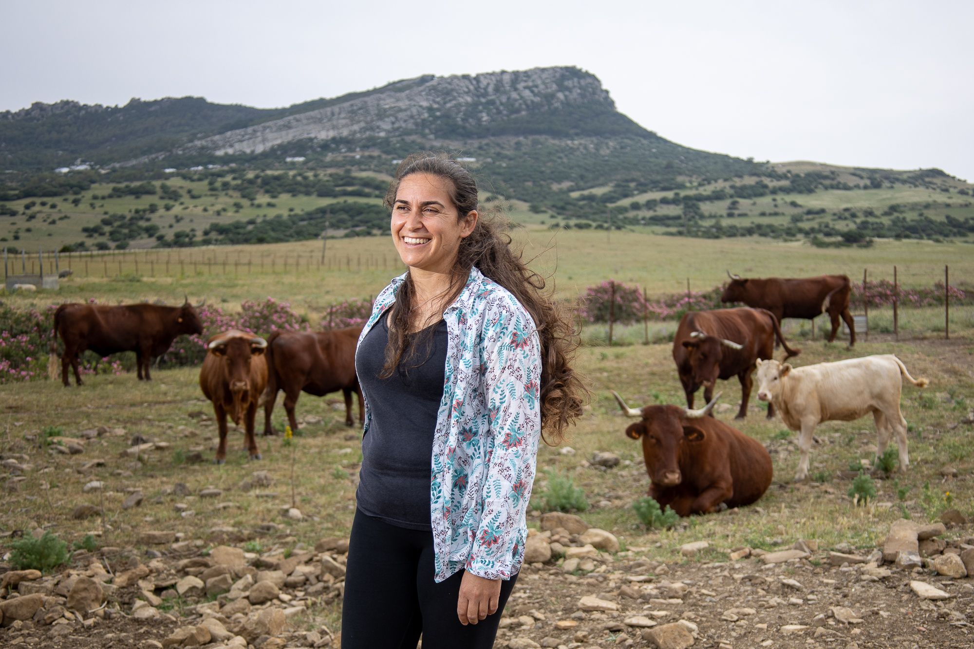 La ganadera Ana Álvarez, con sus vacas retintas detrás, y la Sierra de San Bartolomé al fondo.