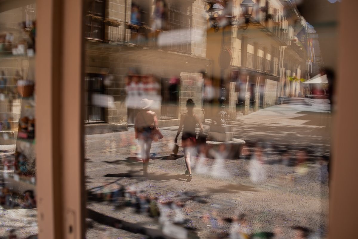Ocupaciones veraniegas. Dos turistas reflejados en el escaparate de un comercio, en una imagen reciente.