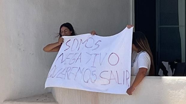 Jóvenes encerradas en el hotel de Mallorca, con una pancarta.