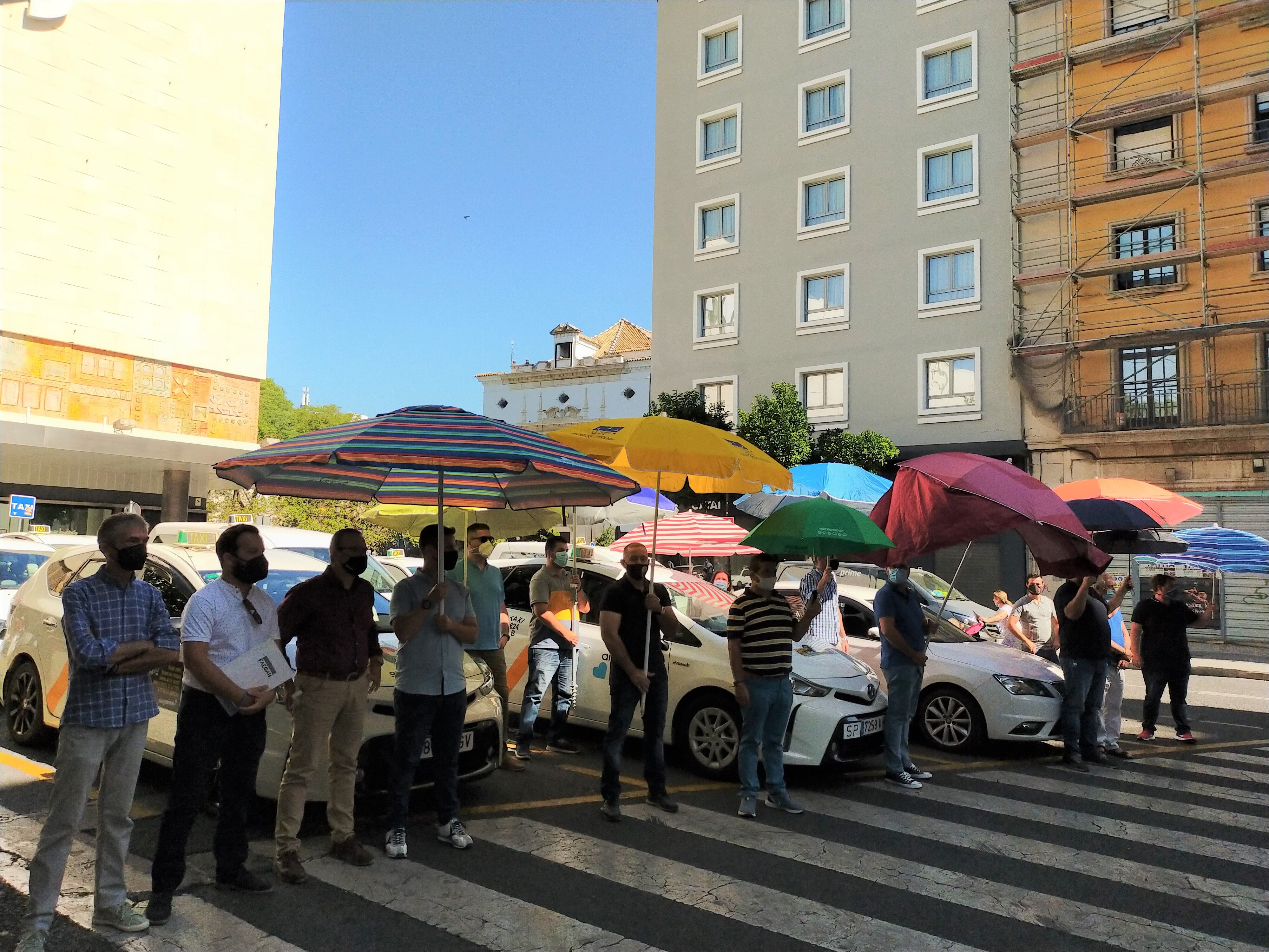 Una 'performance' con sombrillas y paraguas de los taxistas sevillanos para exigir los toldos en el centro.