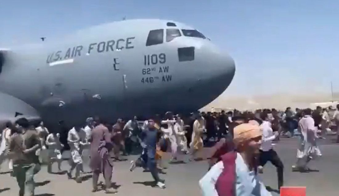 Personas corren alrededor de un avión americano cuando va a despegar.