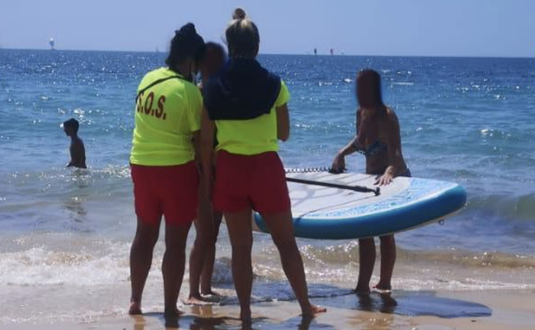 Socorristas con una joven y una tabla de paddle surf en una fotografía de archivo.