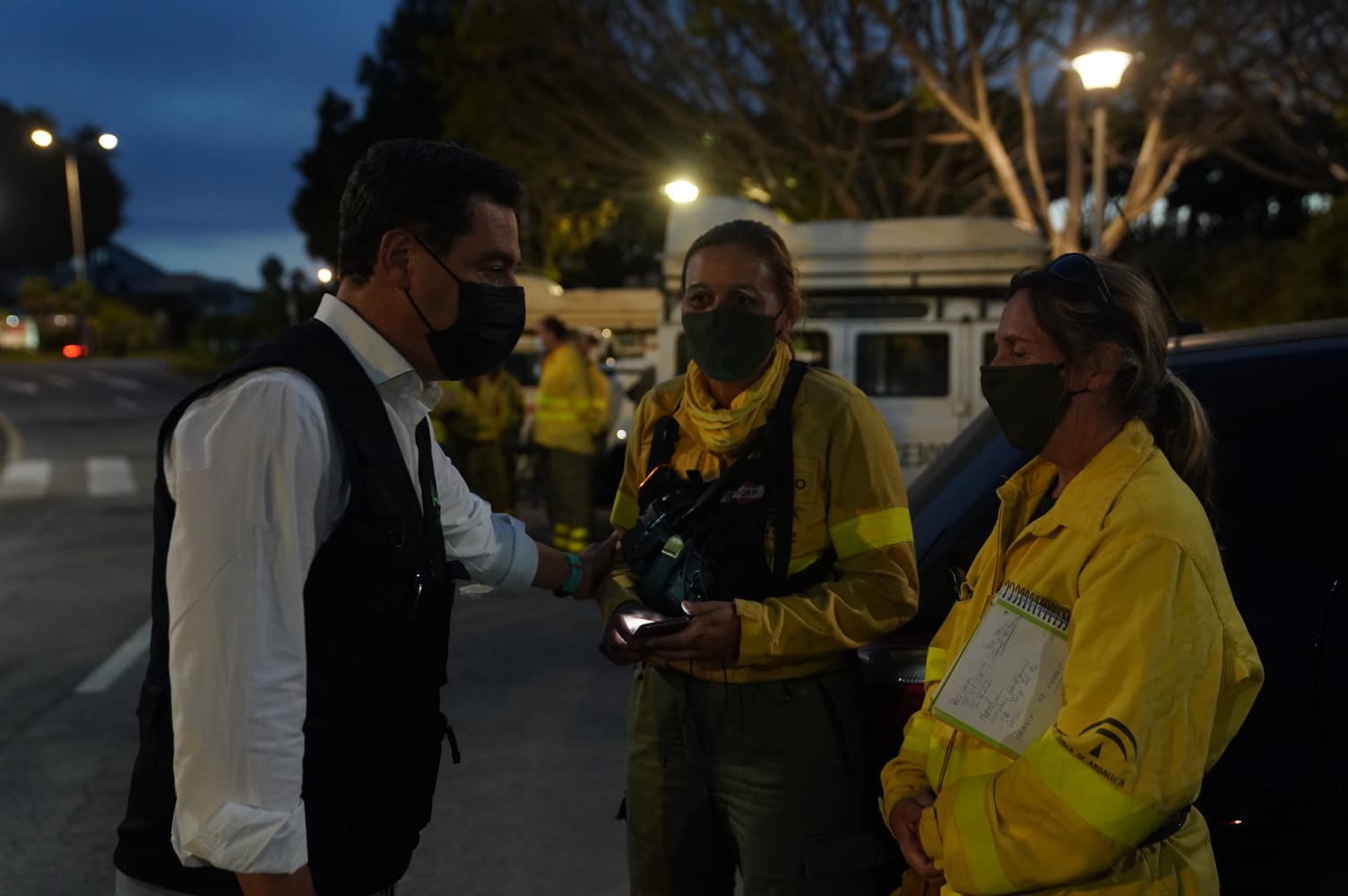 Juanma Moreno dialoga con dos de las agentes forestales que están trabajando en las labores de extinción del incendio.