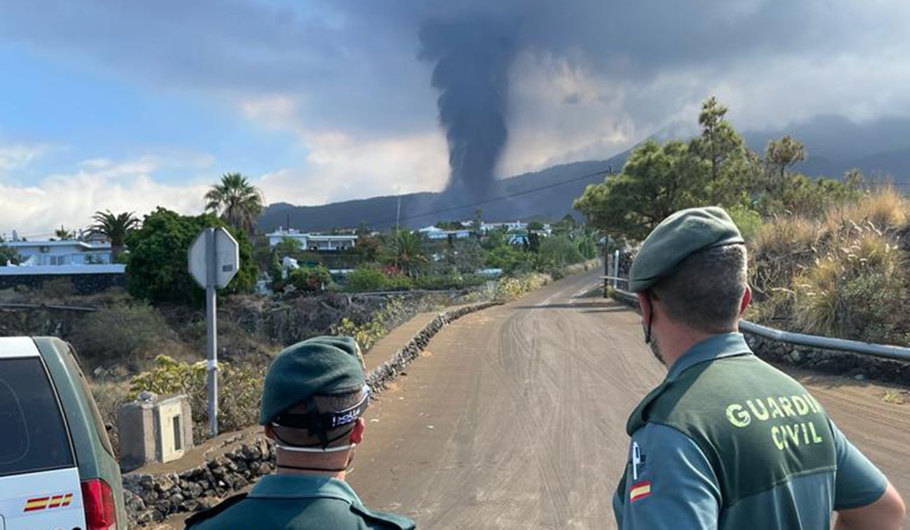 Dos agentes de la Guardia Civil contemplan una nueva erupción del volcán de La Palma.