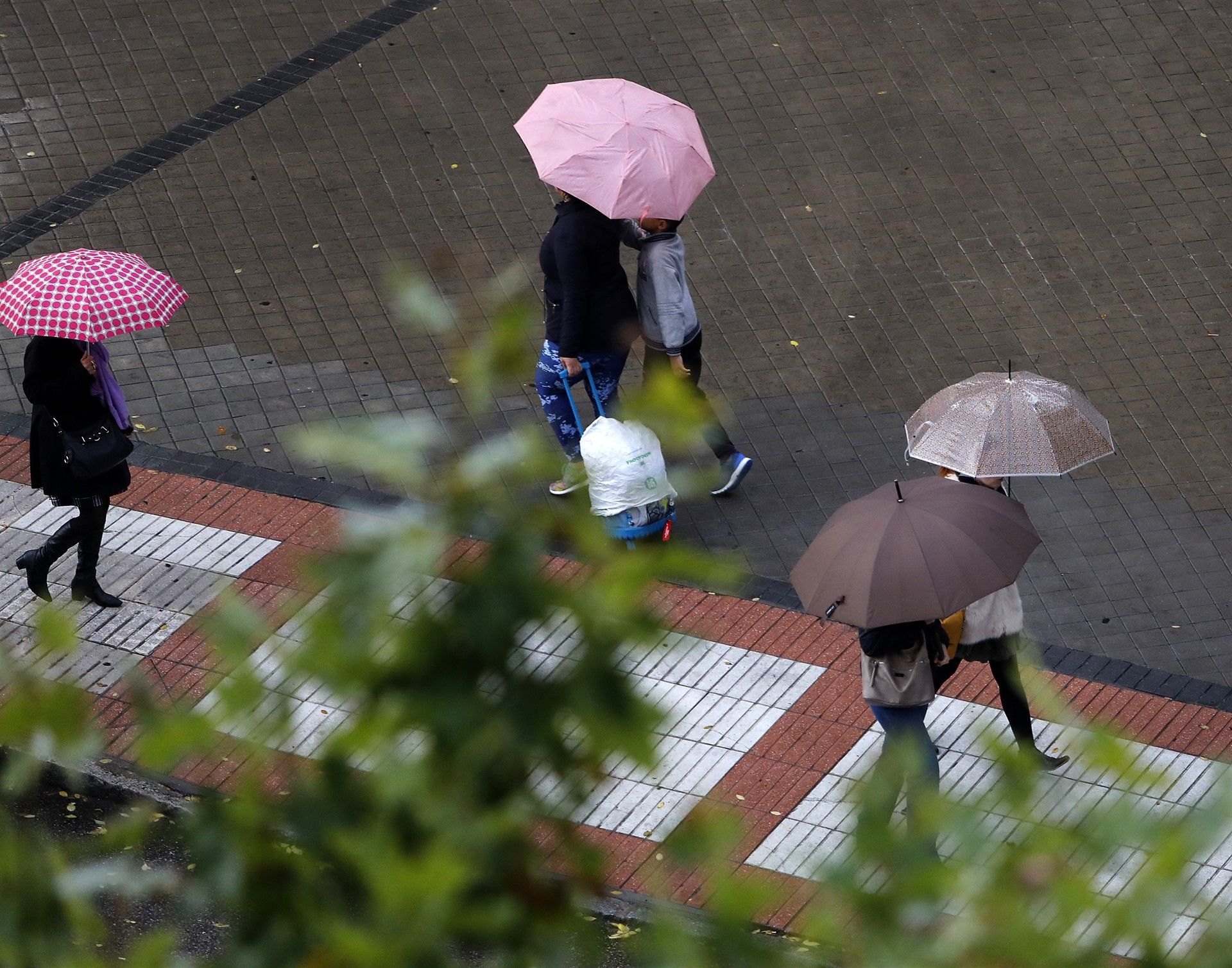 Personas paseando con paraguas bajo la lluvia. FOTO: MARTA FERNÁNDEZ JARA. 