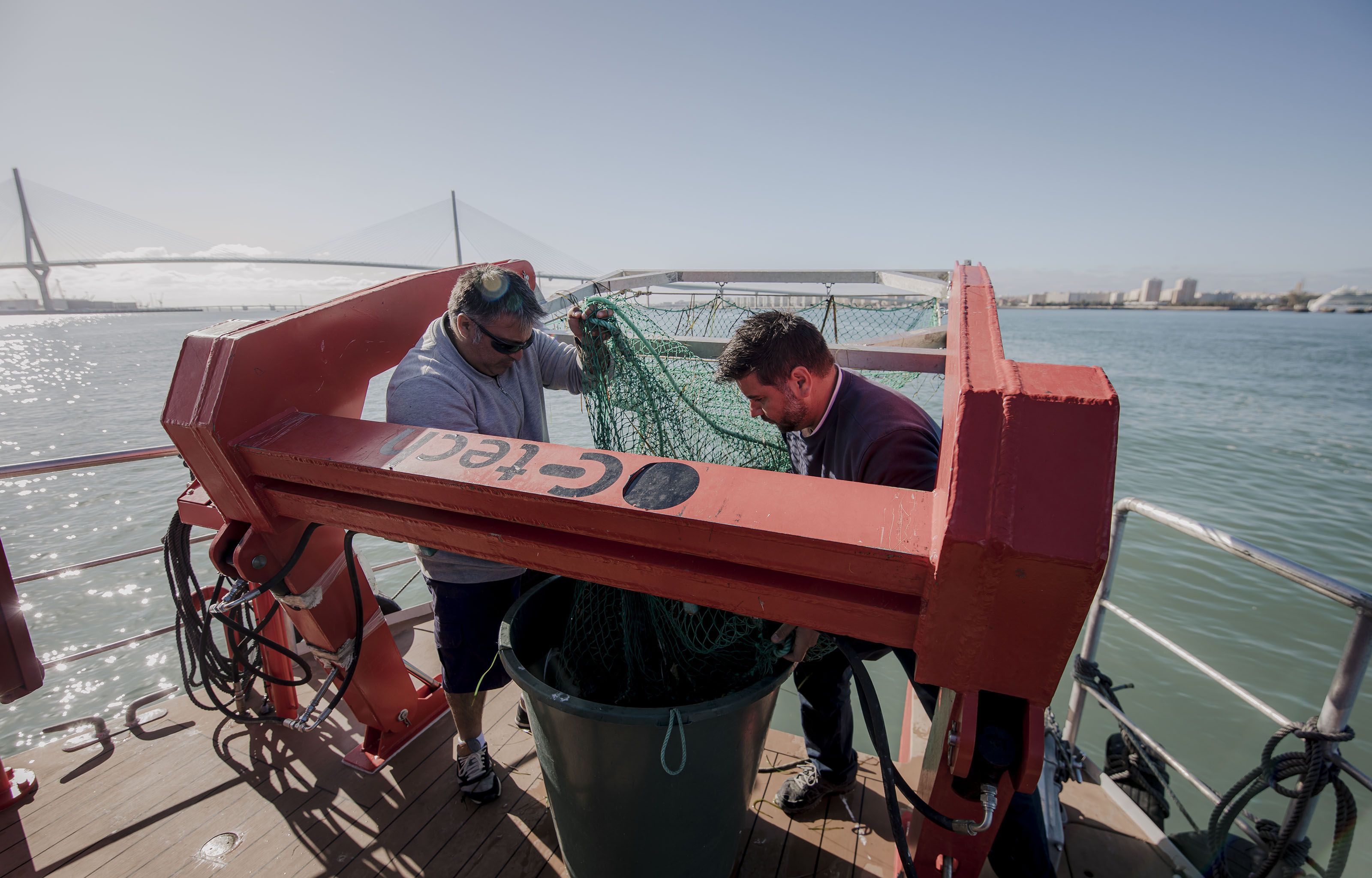 Marcelo y José Luis 'El Pipa' recogen los residuos capturados por la red del barco que limpia la Bahía de Cádiz.