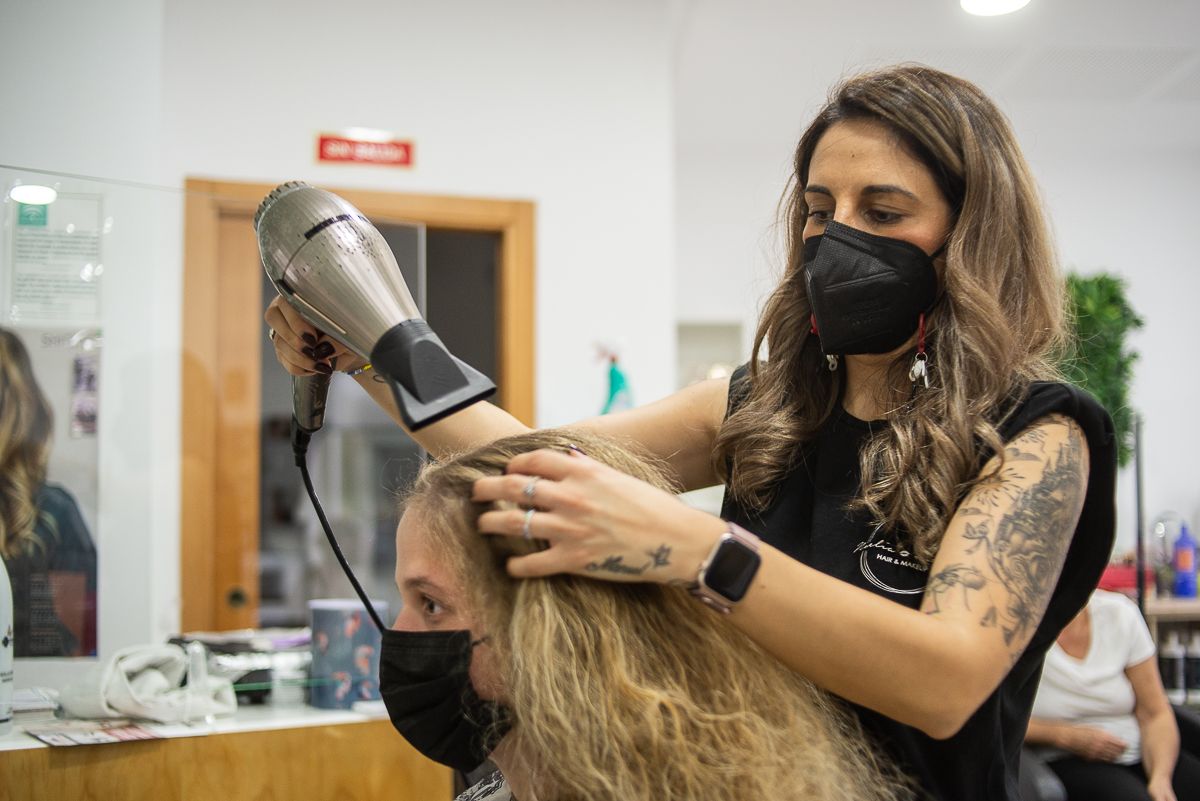 Noelia peina a una clienta en la peluquería.