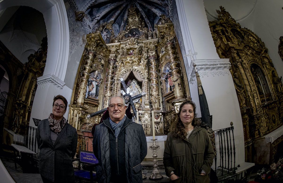 El hermano mayor Feliciano Pérez de Azpillaga entre las restauradoras del retablo que preside el templo.