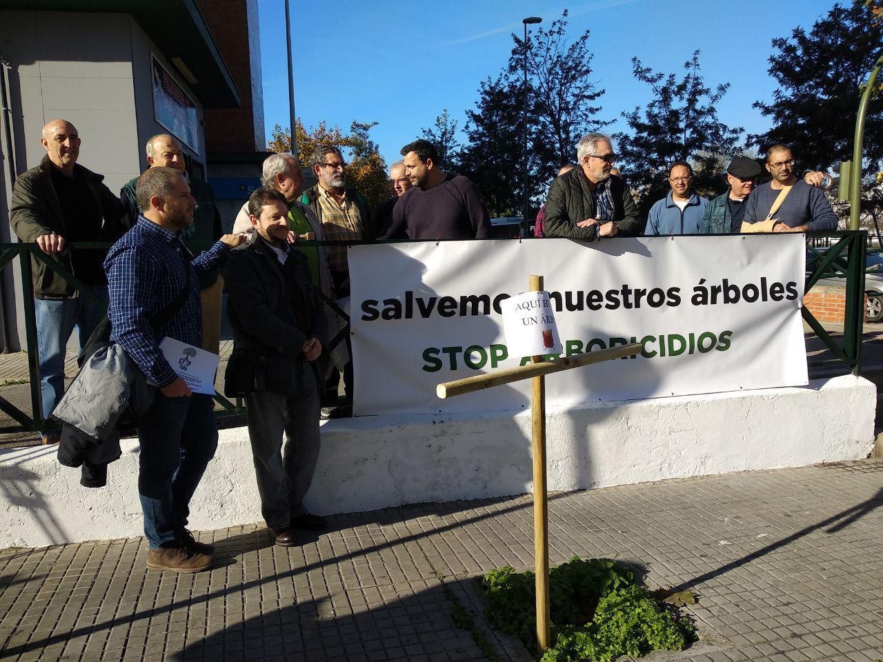 Los manifestantes frente a la cruz plantada en uno de los alcorques vacíos con el cartel "Aquí hubo un árbol".