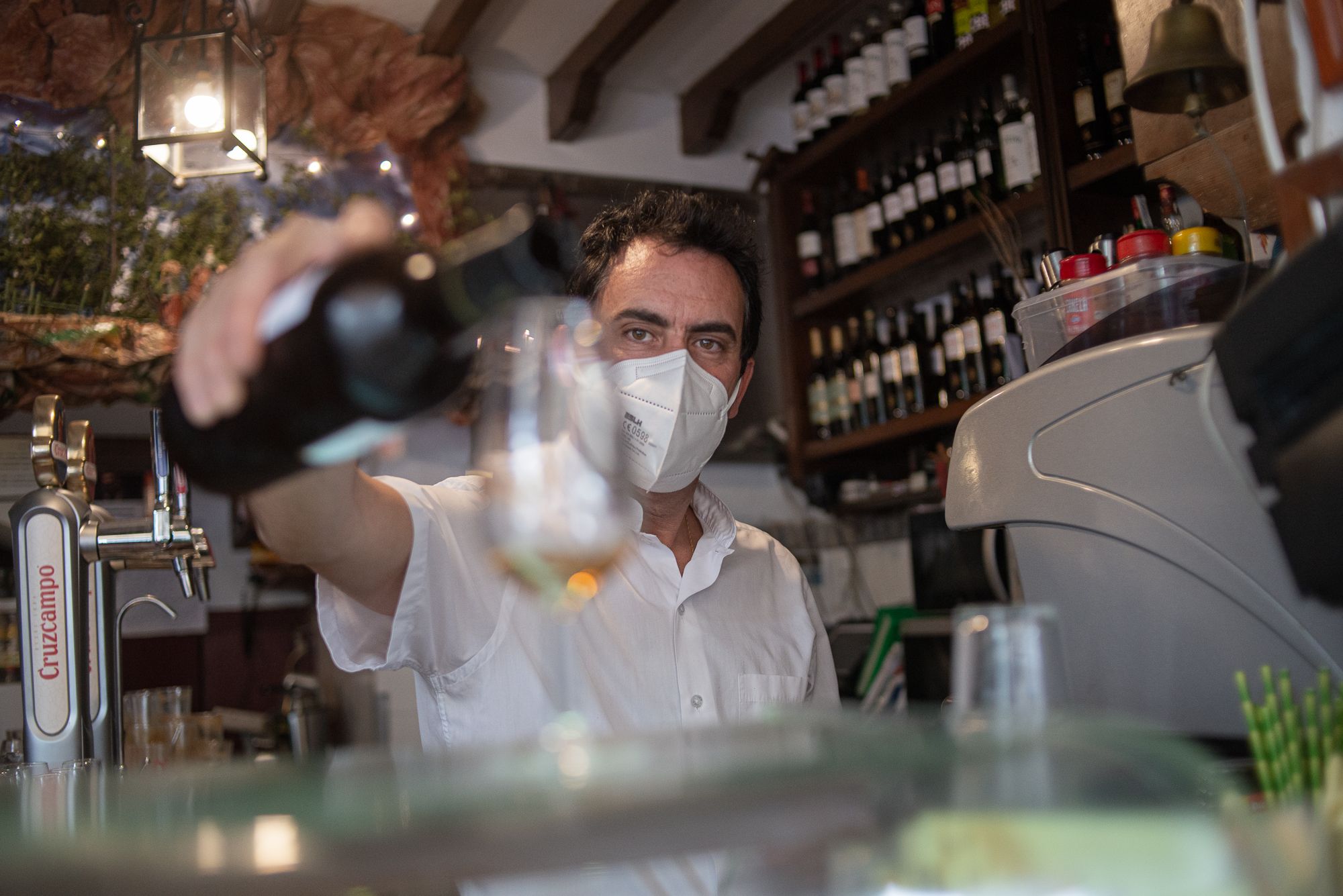 Un camarero sirviendo una copa de vino.