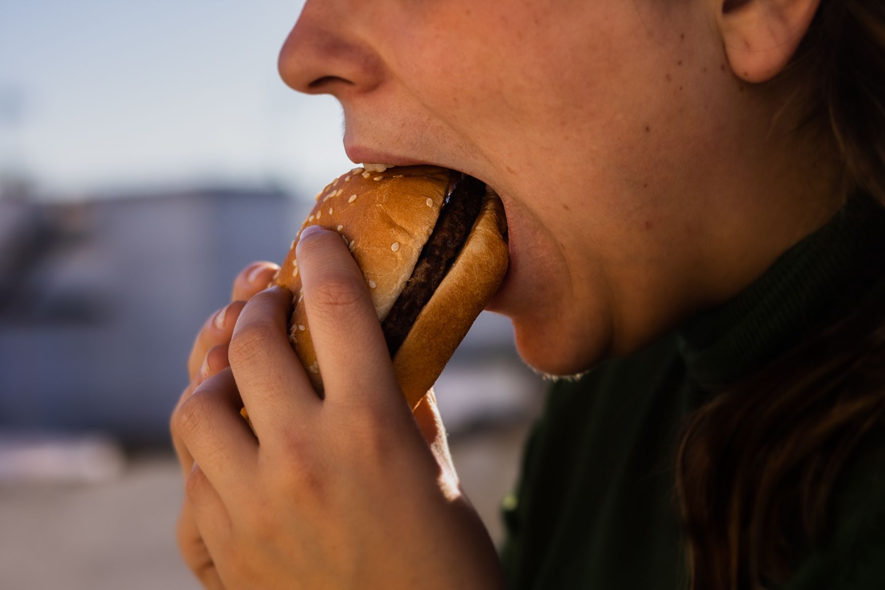 Una mujer comiendo una hamburguesa.