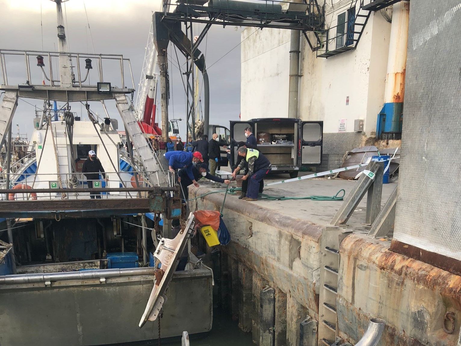 Los pescadores y la Policía  trasladan el cuerpo encontrado por el barco pesquero en Sanlúcar en un cubo.
