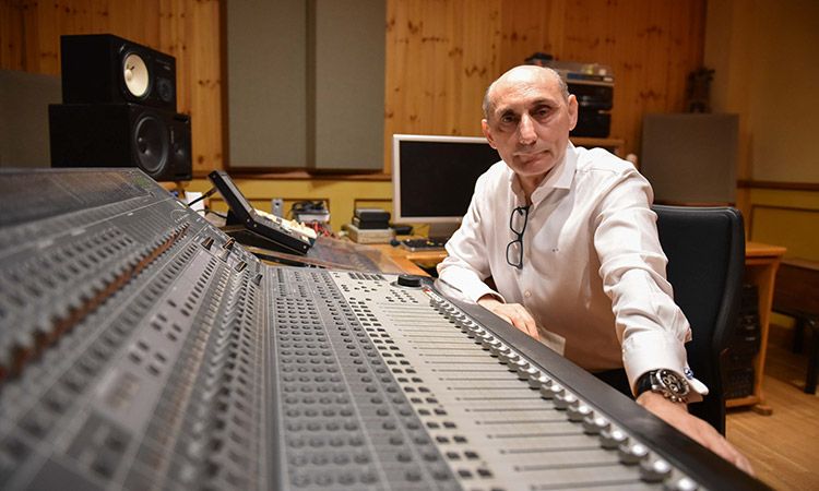 El compositor Manuel Marvizón sentado ante una mesa de mezcla de sonido en un estudio de grabación.
