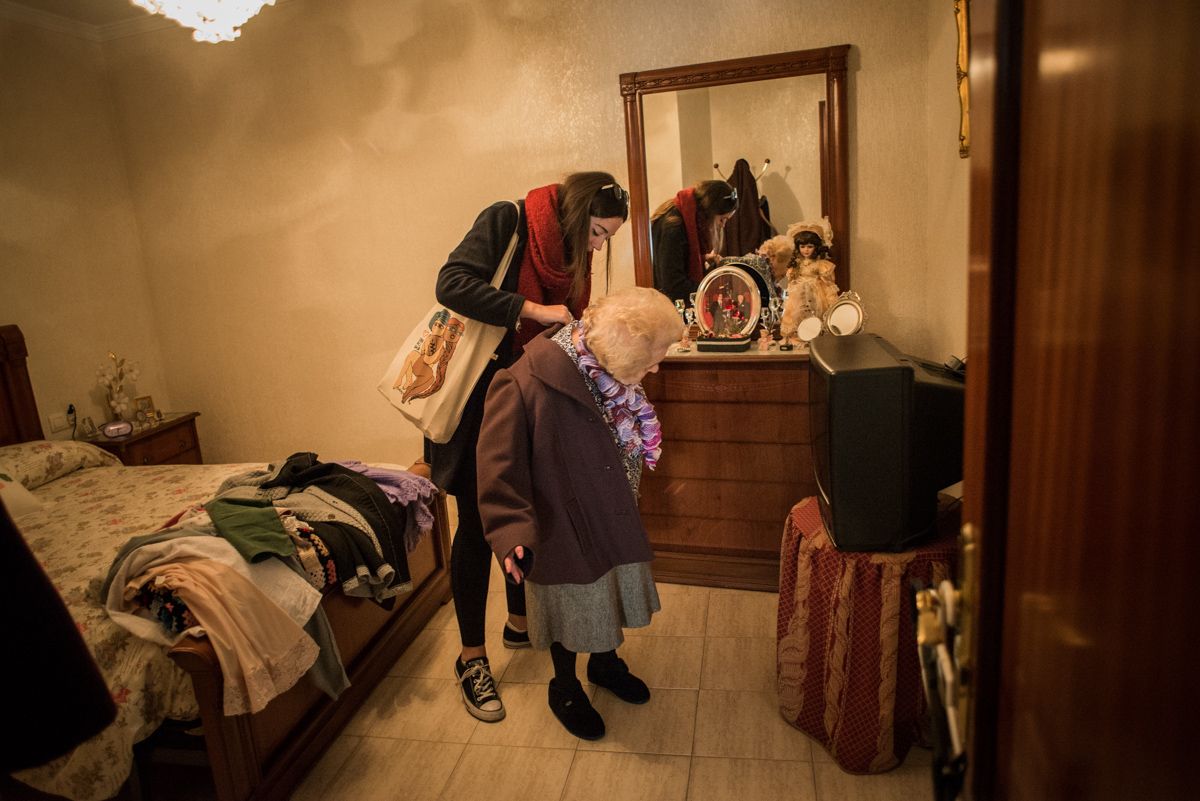Una joven ayudando a una anciana a colocarse el abrigo. FOTO: MANU GARCÍA. 