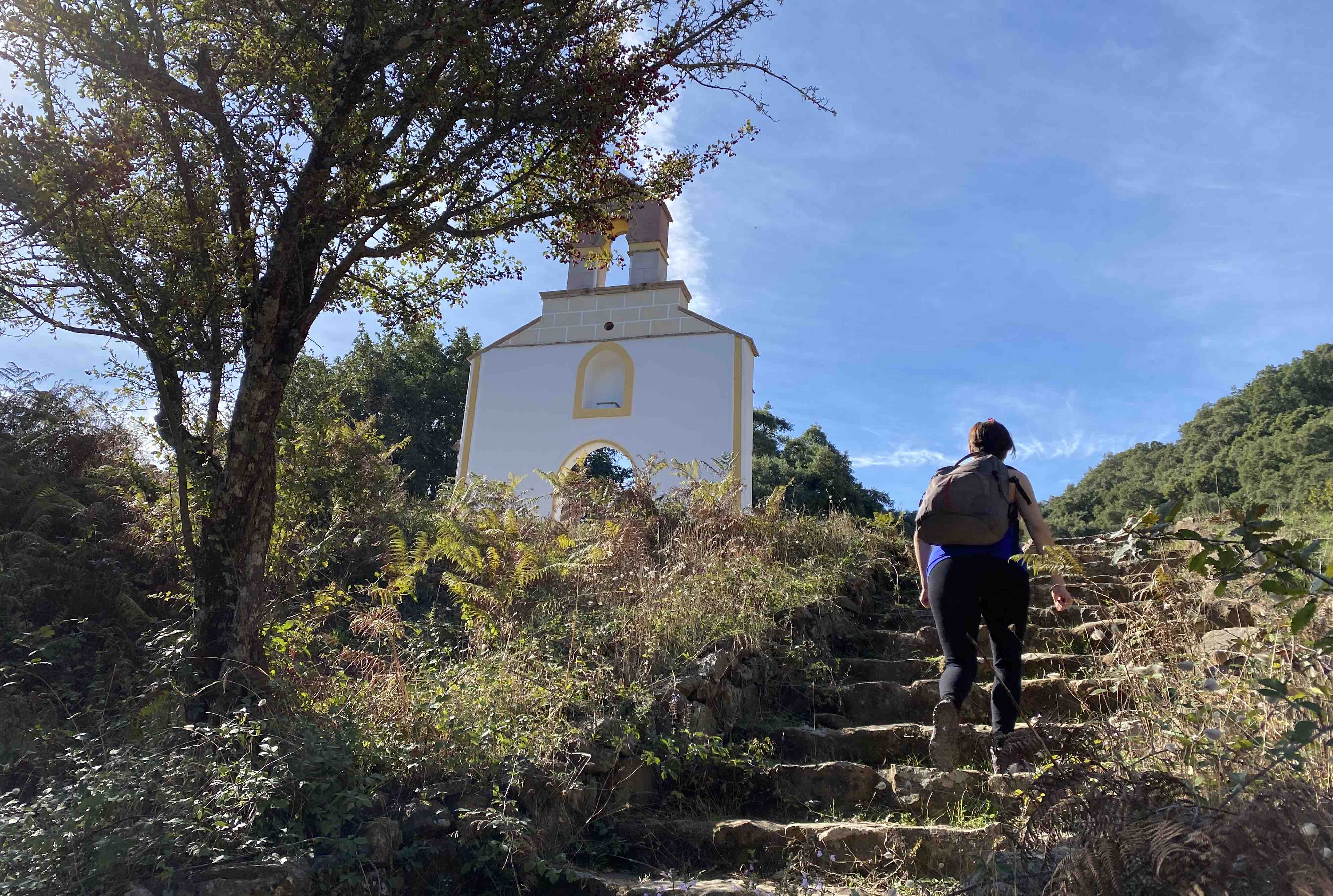 Una excursionista alcanza el valle donde se alzan los restos de la Ermita de La Sauceda, con su fachada recién recuperada.