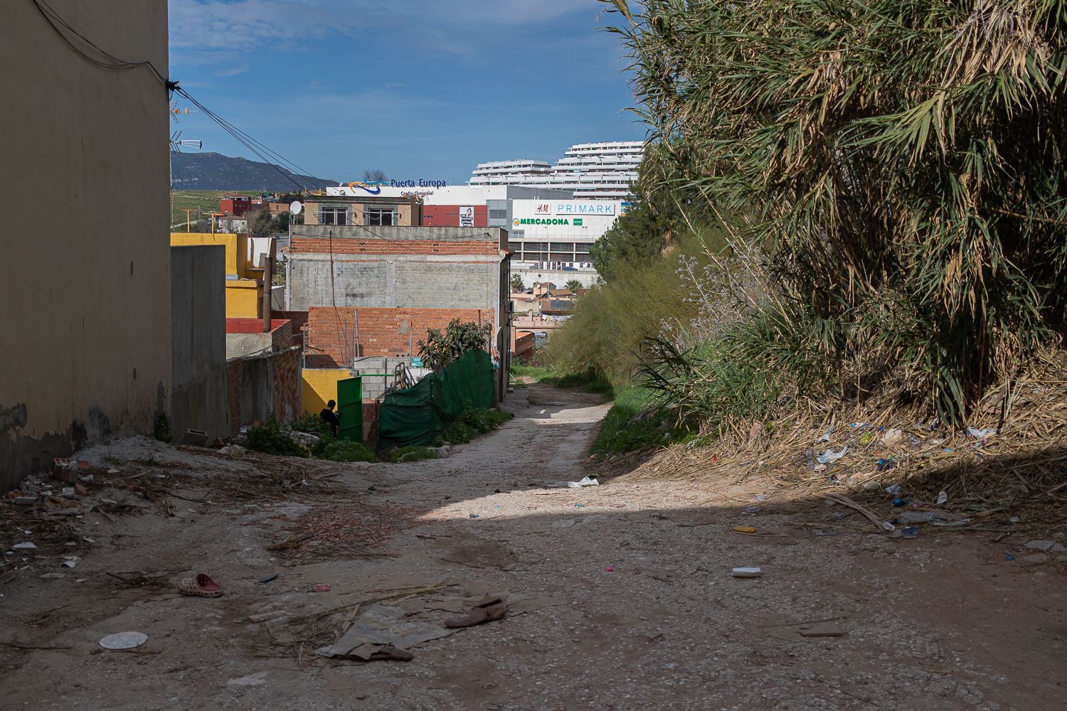 En primer plano, calles de una de las zonas más abandonadas de La Bajadilla. Al fondo, el centro comercial Punta de Europa