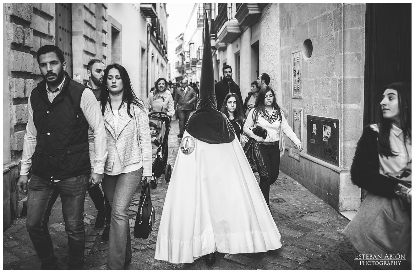 Un nazareno de la Hermandad de la Paz por la calle Tornería, vía clave de paso de cofradías en el Martes Santo.